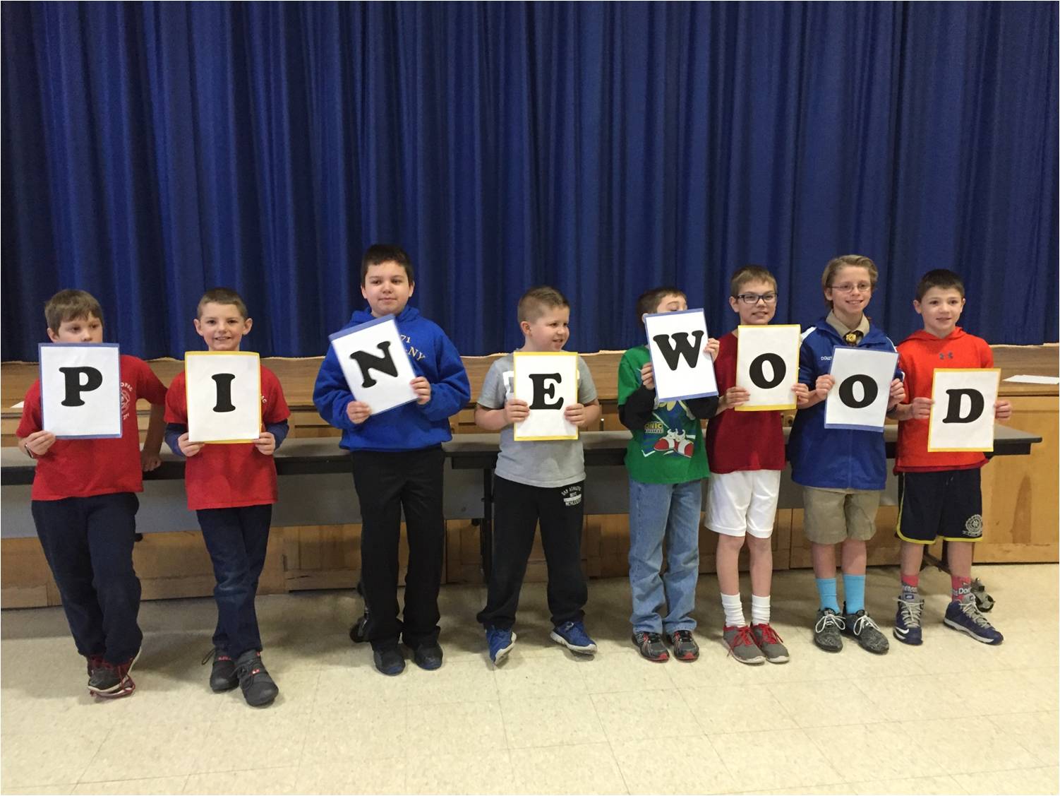 Scouts holding pinewood derby signs.